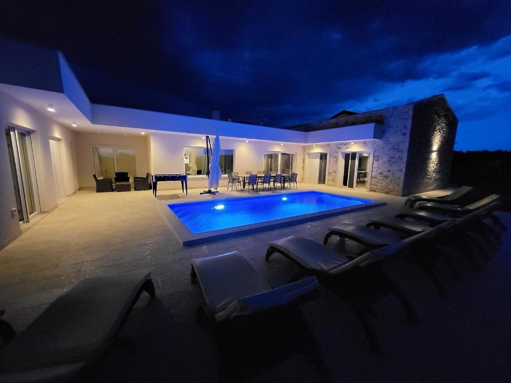 乌马格Villa Mare e Monti with heated pool的游泳池周围设有躺椅,晚上