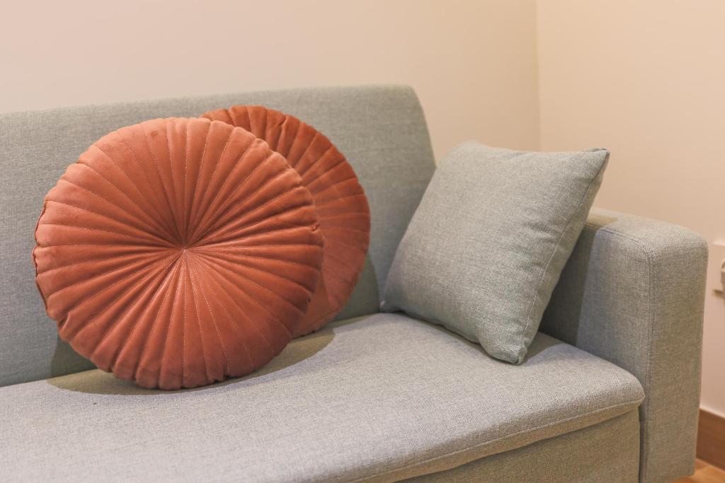 阿利坎特Dorinda Rooms的橙色枕头坐在带枕头的灰色沙发上