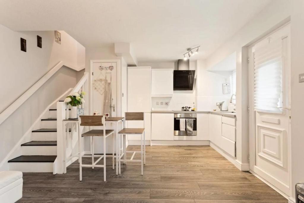 ThamesmeadSnug & Cosy Home In Thamesmead Overlooking A Park的白色的厨房设有楼梯和桌椅