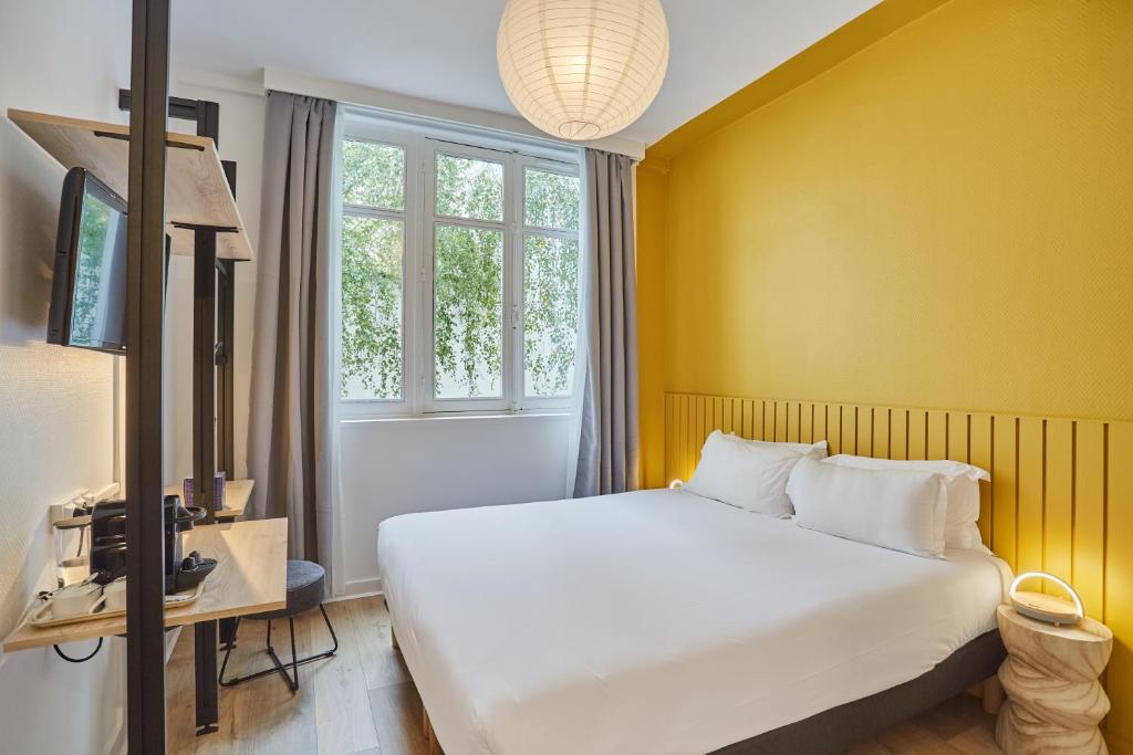 巴黎Hôtel Beauquartier Montmartre的卧室配有白色的床和黄色的墙壁