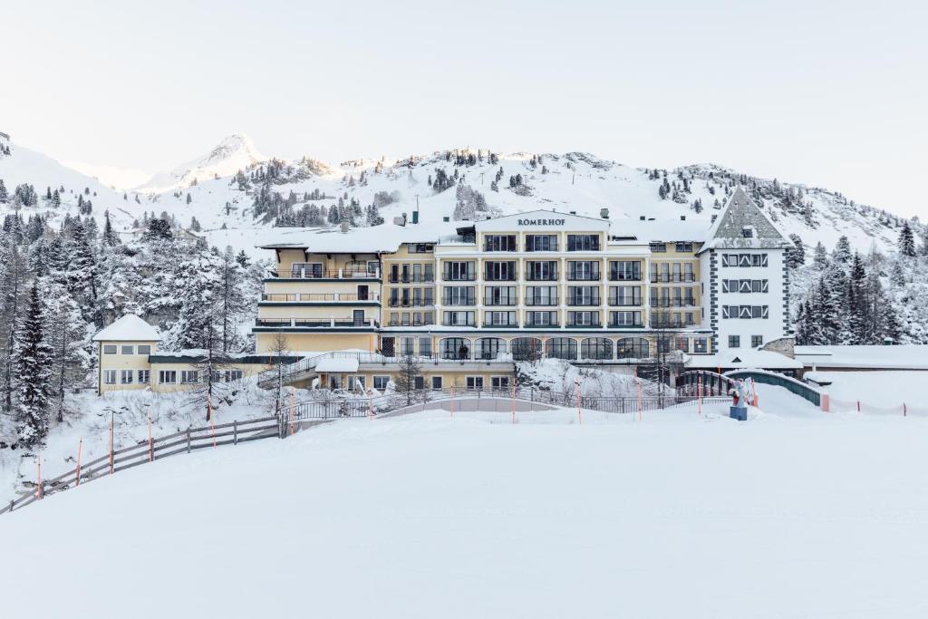 上陶恩Hotel Römerhof Superior的一座大建筑,位于一座白雪覆盖的山顶上