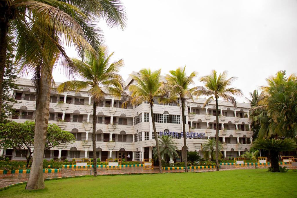 AmargolNaveen Residency的一座白色的大建筑,前面有棕榈树