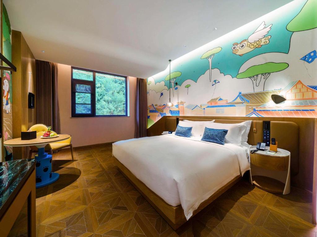 乡宁云丘山诺富特酒店的卧室配有一张大床,墙上挂有绘画作品