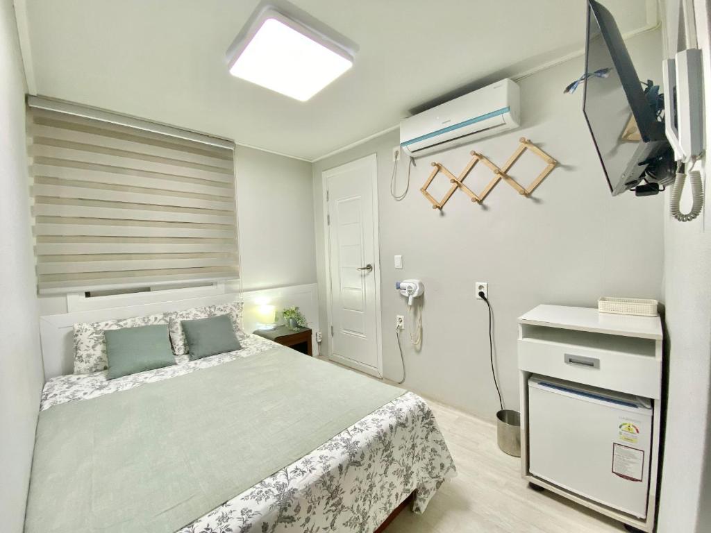 首尔JIBIDA Urban Inn的一间卧室配有一张床和一台电视
