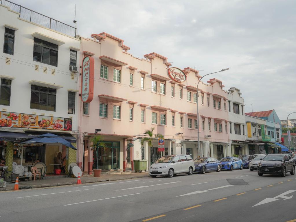 新加坡Amrise Hotel的一条街道,汽车停在粉红色建筑前面