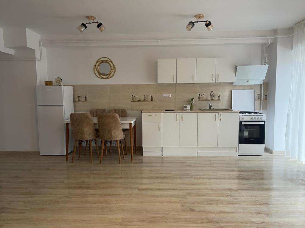 拉姆尼库沃尔恰Apartament YRA Rm.Valcea的厨房配有白色橱柜和桌椅