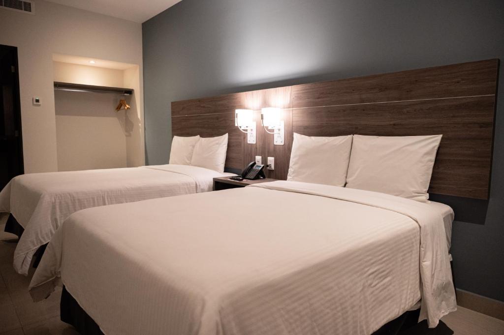 蒙特雷Hotel Centria的配有白色床单的酒店客房内的两张床