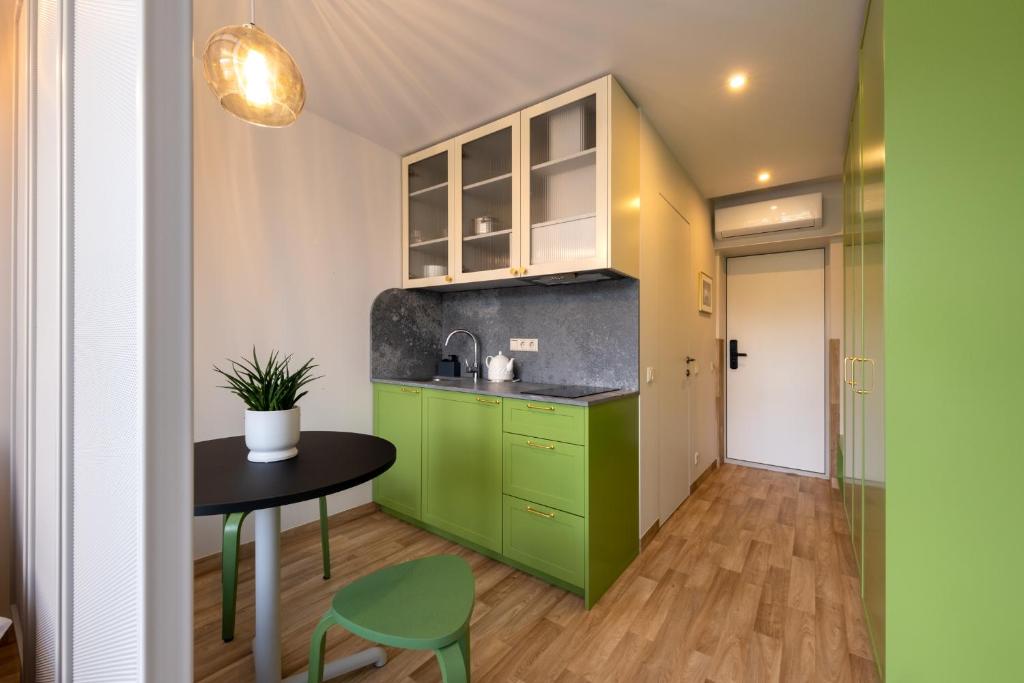 克莱佩达Berlin Studios的厨房配有绿色橱柜和桌椅