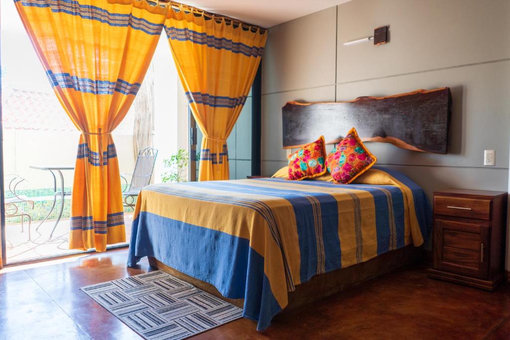 埃斯孔迪多港Madre Tierra Hotel & Coworking & Hostal的一间卧室配有带橙色窗帘的床和窗户