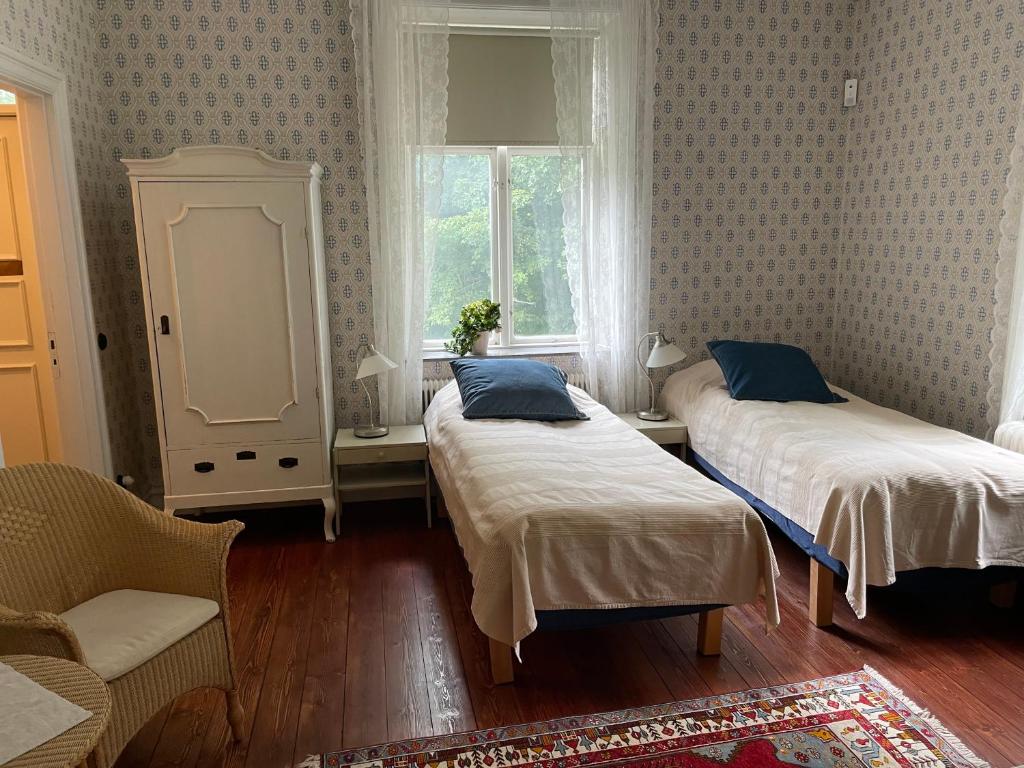 FlyingeRum på Gårdstånga Prästgård的一间卧室设有两张床、一把椅子和一个窗户。