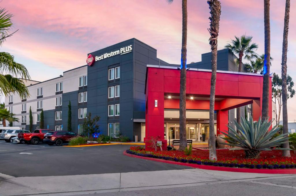 洛杉矶华美达商务酒店的拥有棕榈树的红色和黑色建筑的酒店