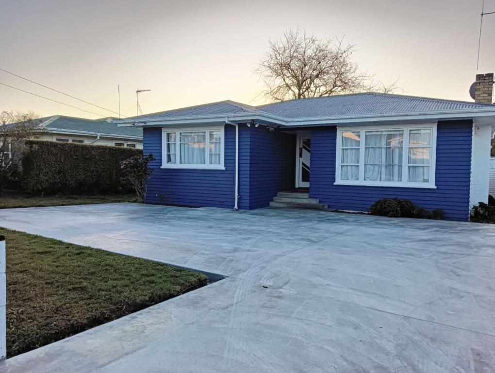 汉密尔顿Melville Guest House near Waikato Hospital的前面有车道的蓝色房子