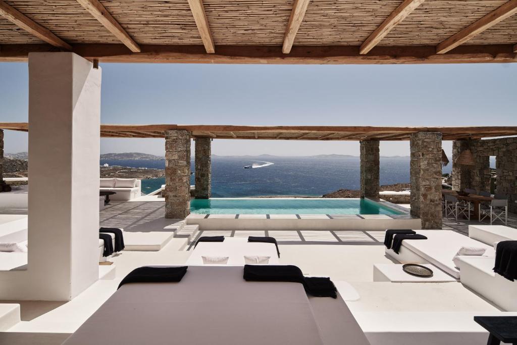 胡拉吉亚Villa La Piscine Mykonos的一间设有白色桌椅的房间和一个游泳池