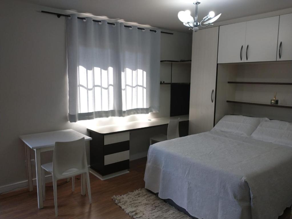 圣若泽杜斯皮尼艾斯Residencial Vitor Studio 5的一间卧室配有一张床、一张书桌和一个窗户。