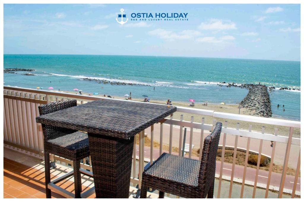 丽都迪奥斯蒂亚Ostia Holiday Sunset的俯瞰海滩的阳台配有桌椅