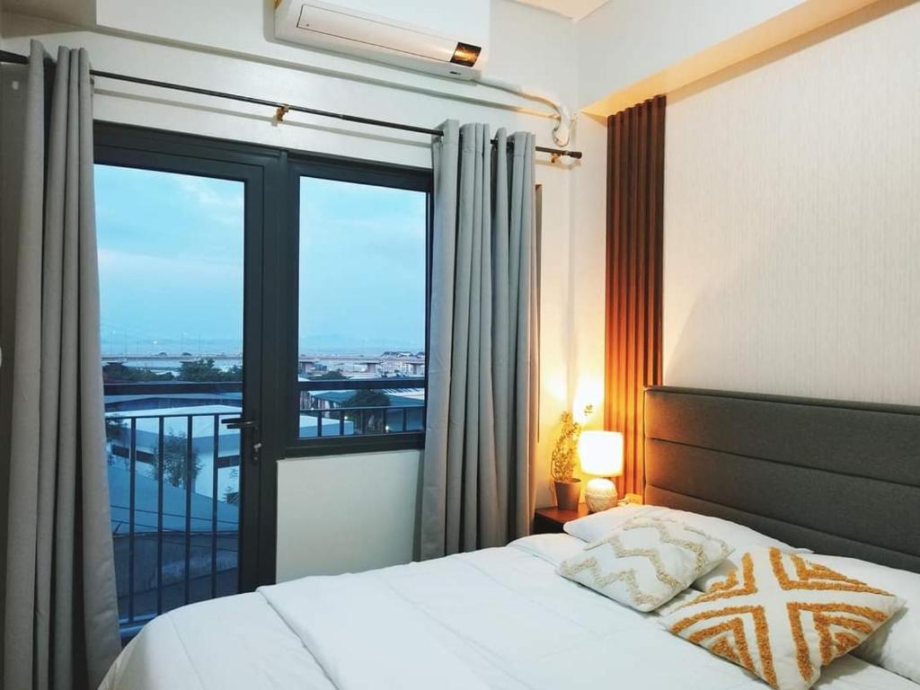 马尼拉2BR SMDC Bloom Residences Near NAIA Wi-fi +Netflix的一间卧室设有一张床和一个大窗户
