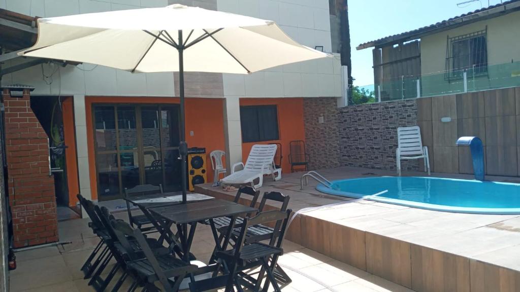 JaguaribeLinda Casa Itamaracá的游泳池旁配有遮阳伞的桌椅