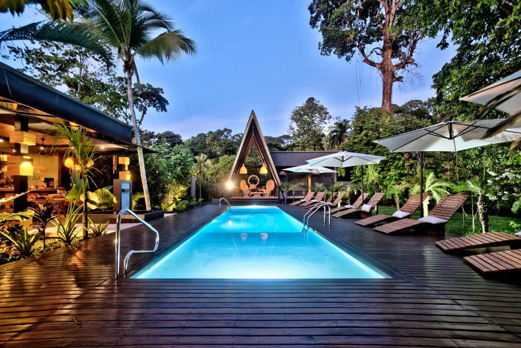 别霍港Namu Garden Hotel & Spa的度假村的游泳池,配有椅子和遮阳伞