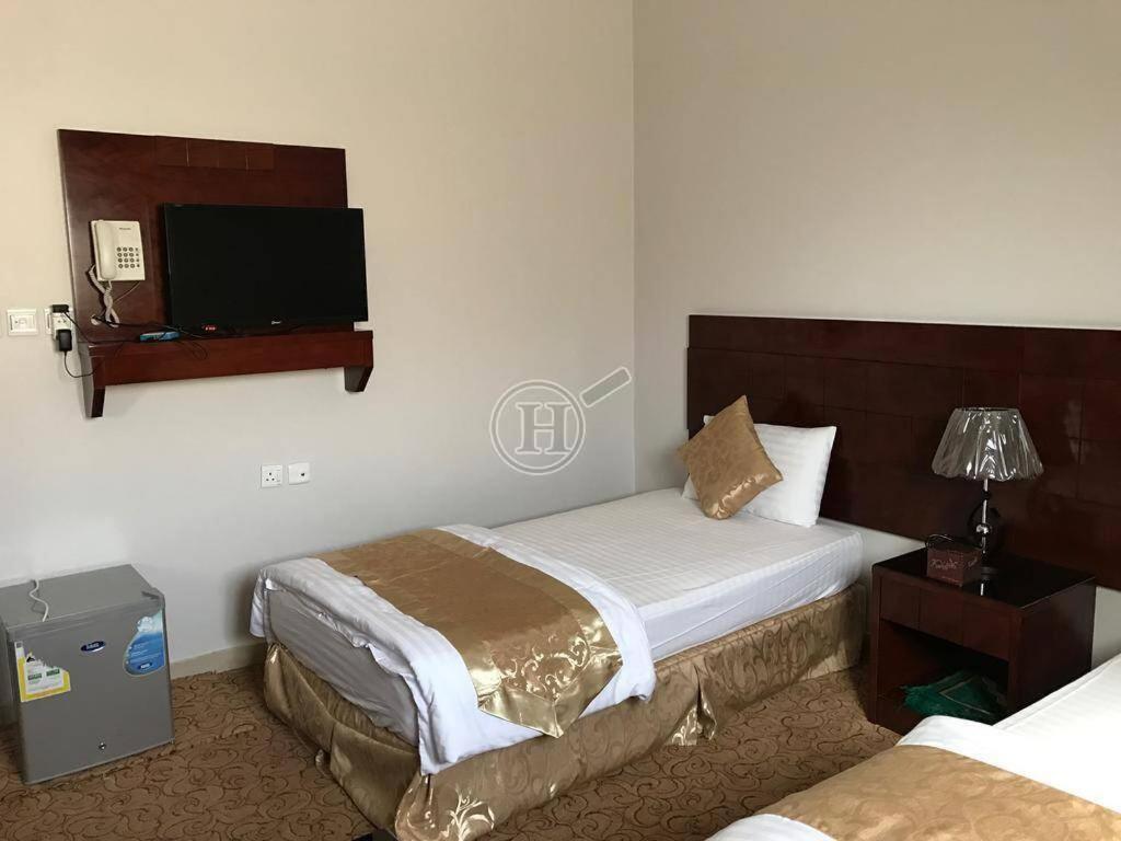 哈伊勒رسلين للشقق المخدومة的酒店客房设有两张床和一台平面电视。