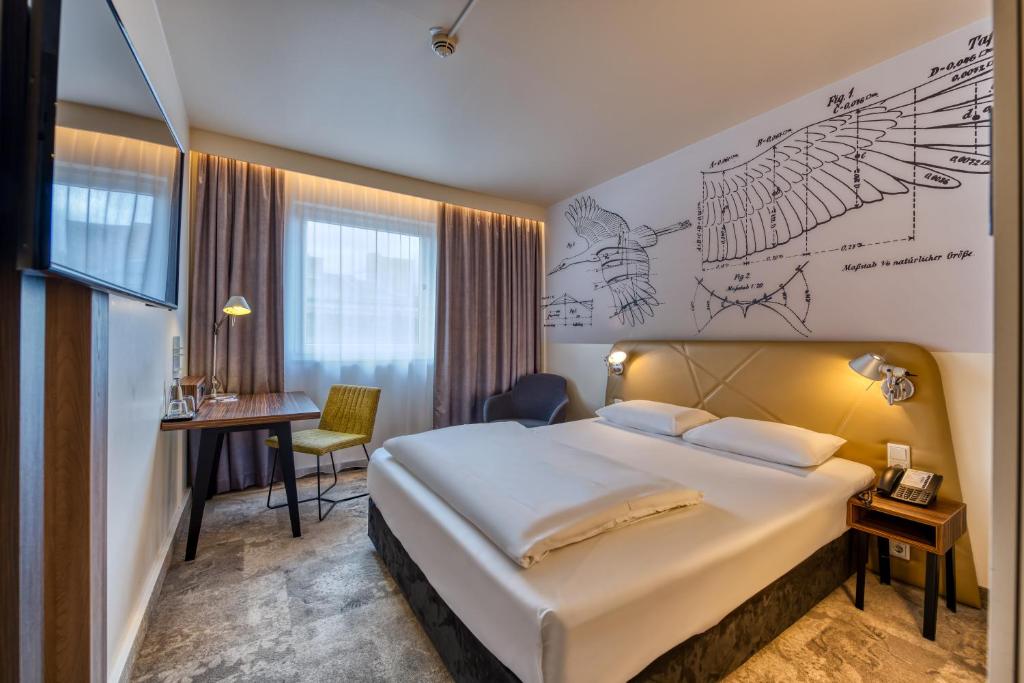 柏林柏林美居酒店的酒店客房设有一张大床和一张书桌。