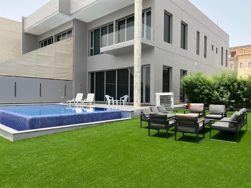 阿尔科兰Sama Chalet kuwait的一座房子,设有一座带游泳池和绿草的庭院