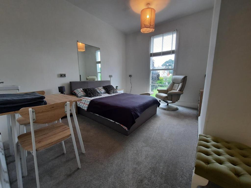 道利什Dawlish Lawn View的一间卧室配有一张床、一张书桌和一个窗户。