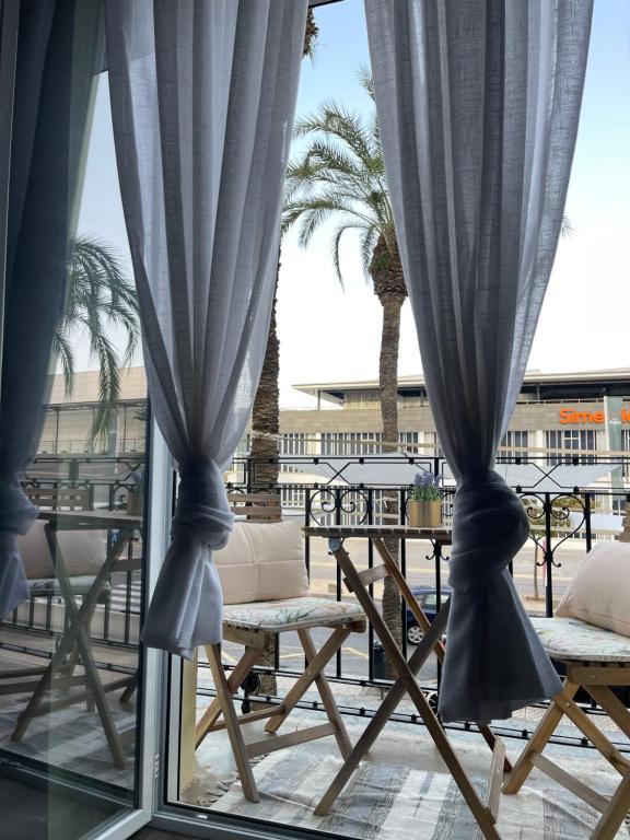 格拉德卡斯特利翁Centrally Located Spacious Private Apartment BuenaVista in Grao with Rooftop的窗户配有蓝色窗帘和桌子,棕榈树