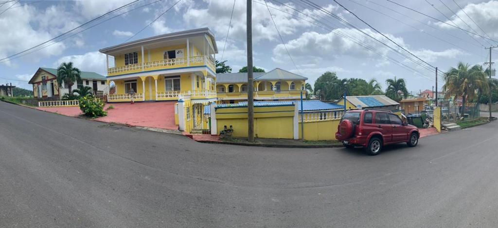 RogerCAPRICE STUDIO & GUEST HOUSE的停在黄色房子前面的红色汽车