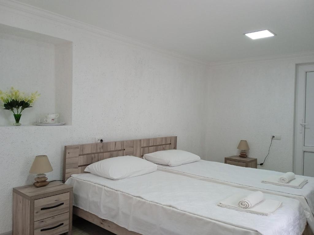 库塔伊西Elegant Hotel的一间卧室配有两张床、白色的床单和毛巾。