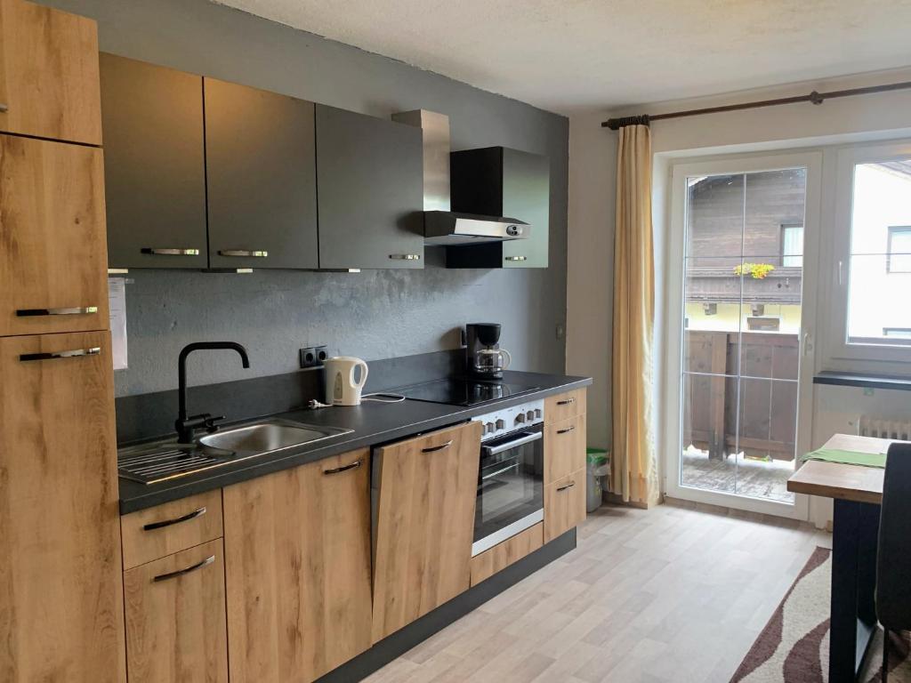 瑟尔Appartements Konrad的厨房配有木制橱柜、水槽和窗户。