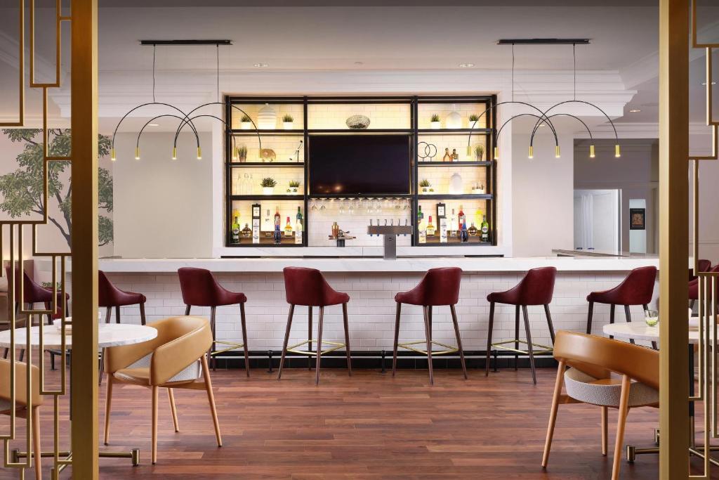 费城费城威斯汀酒店的餐厅设有酒吧,配有红色的椅子和桌子