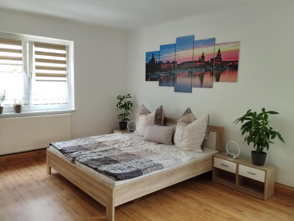 皮尔纳Ferienwohnung "Spatzennest"的卧室配有一张床,墙上挂有绘画作品