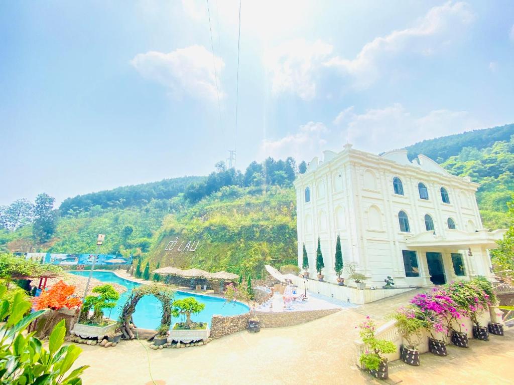 Làng Song CaKhu du lịch sinh thái Cỏ Lau Village的山旁的一座带游泳池的建筑