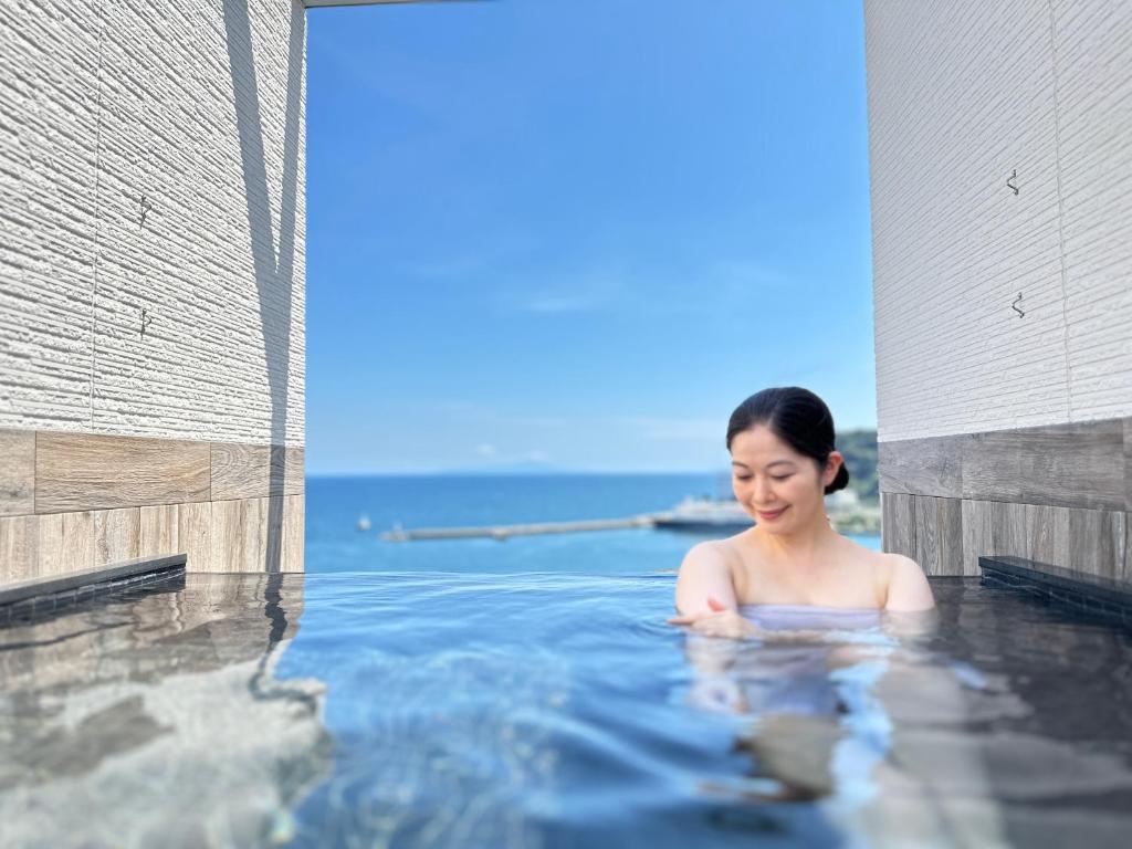 热海热海美景私人温泉公寓式酒店的女人坐在热水浴缸里