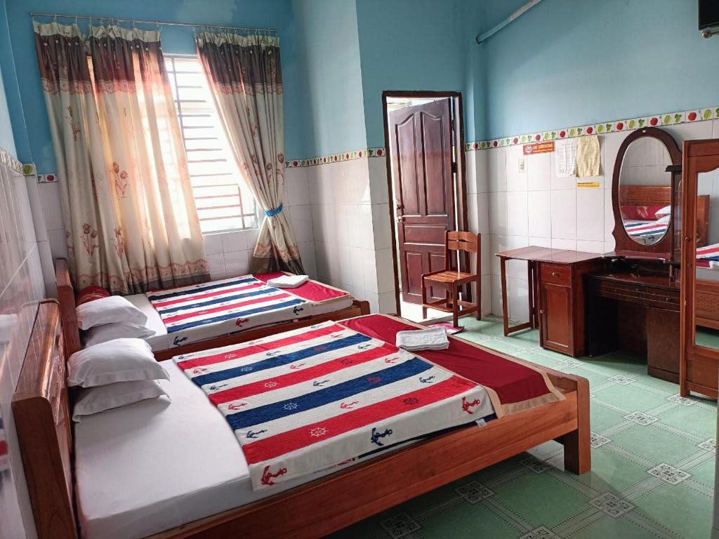 芹苴Khách sạn Ngọc Mai 2的一间卧室配有两张床、一张桌子和一面镜子