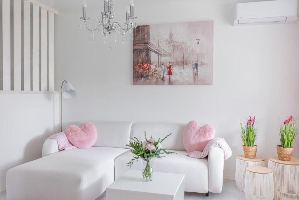 罗瓦涅米City Holiday Apartments 2的客厅配有白色沙发和粉红色椅子