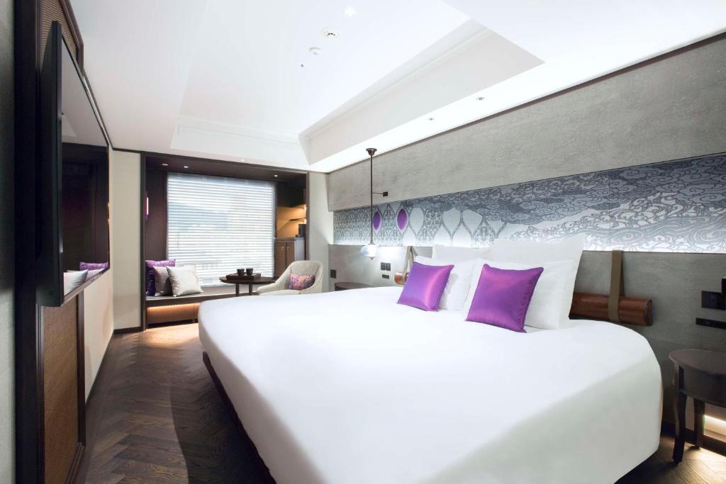 京都Dhawa Yura Kyoto - Banyan Group的卧室配有一张带紫色枕头的大型白色床。
