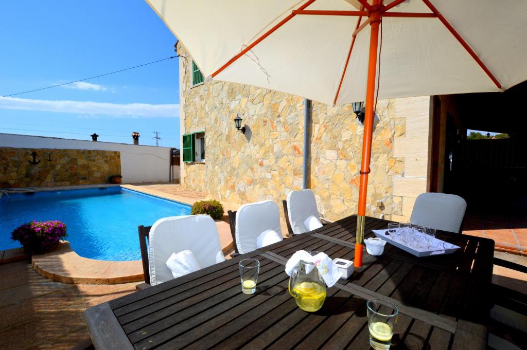 坎帕斯蒂利亚Bonito chalet con piscina cerca del mar的游泳池旁带遮阳伞的桌子