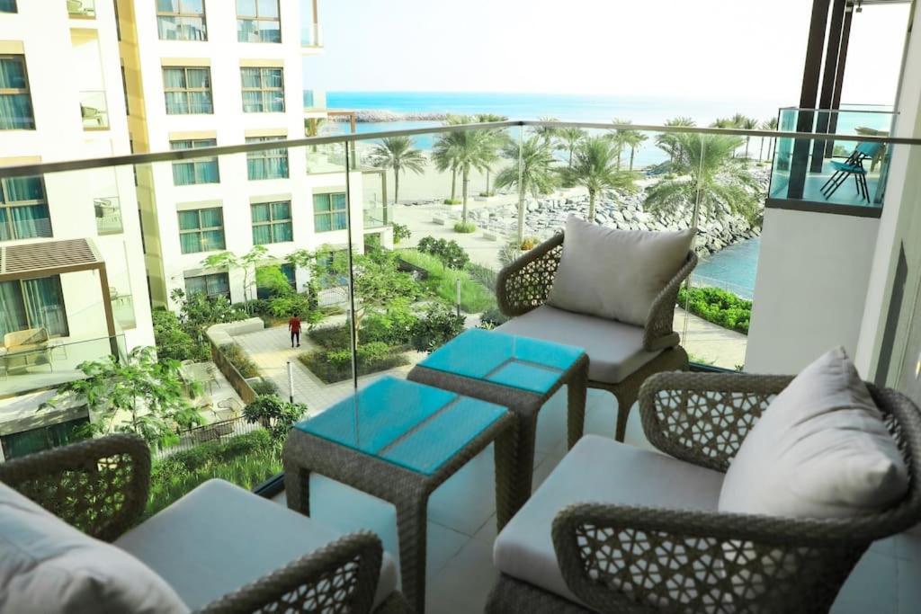 富查伊拉Address Resort Apartments Fujairah - 2 bedroom apartment的阳台配有桌椅,享有海滩美景