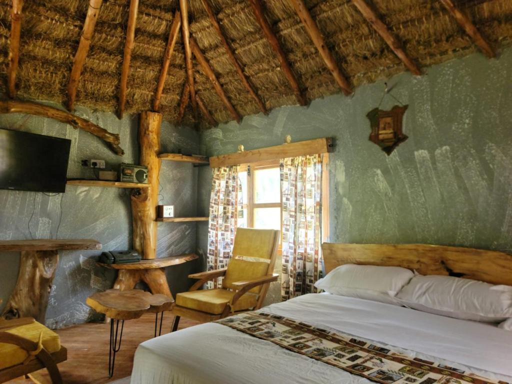 Naro MoruPodocarpus cottages的卧室配有1张床、1张桌子和1把椅子