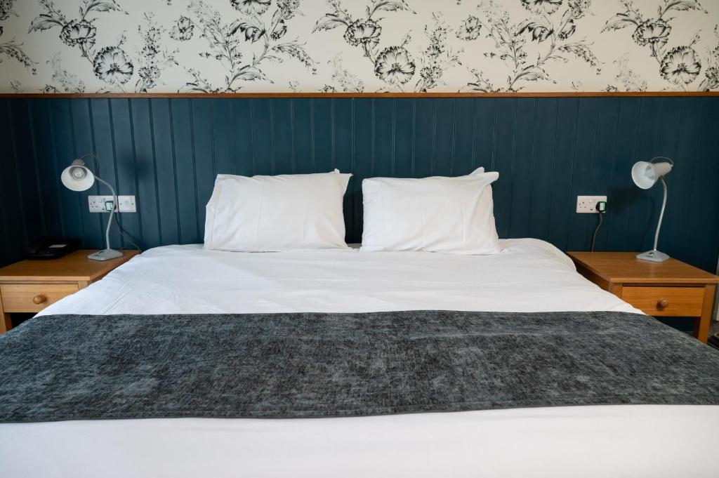 圣伦纳兹St Leonards Hotel by Greene King Inns的一间卧室配有一张带两盏灯和一堵墙的床。