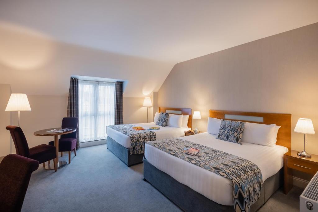 阿森赖拉辛伍兹酒店的酒店客房设有两张床和一张桌子。