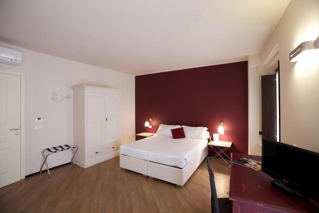 曼托瓦Hotel Leon D'Oro的卧室配有白色的床和红色的墙壁