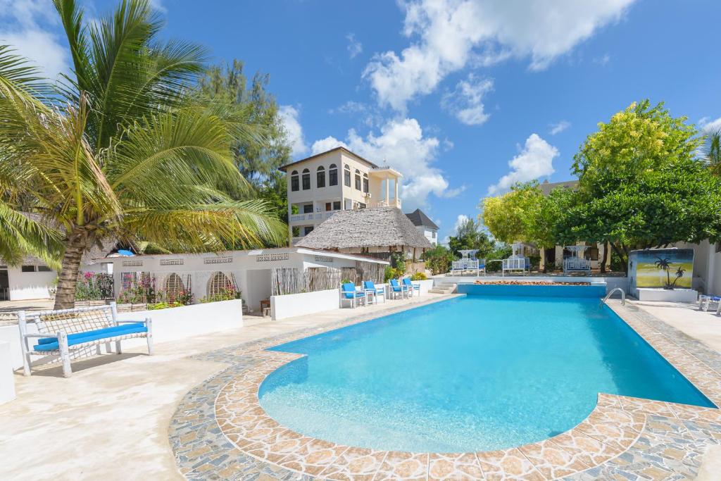 江比阿Geo Zanzibar Resort的一个带椅子的游泳池和一个背景建筑