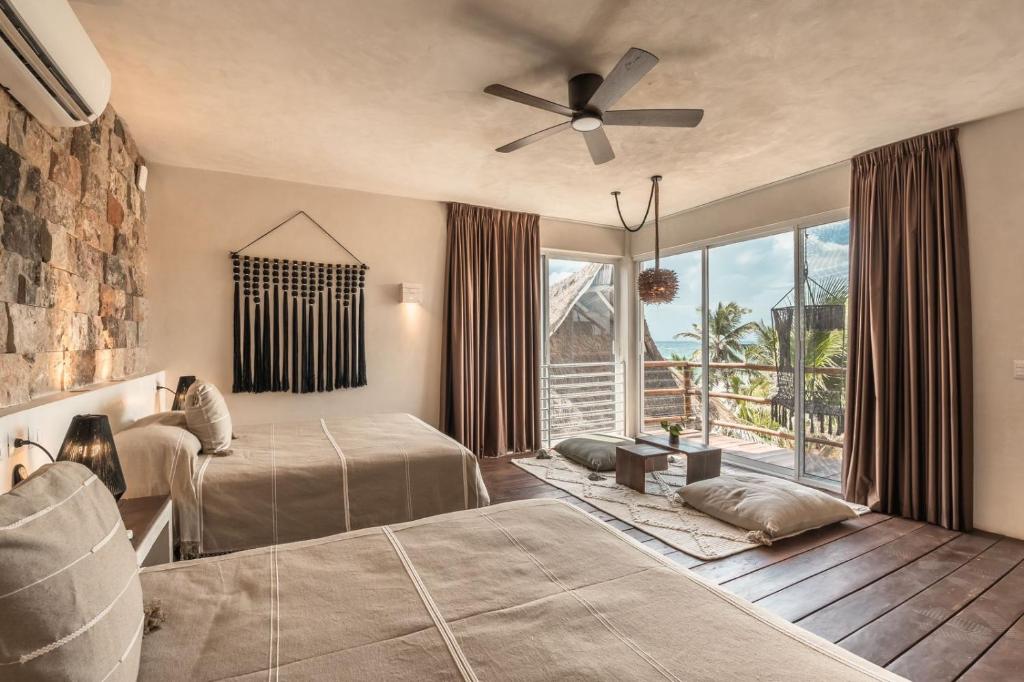 图卢姆Niken Beachfront Tulum Hotel的一间卧室配有两张床和吊扇