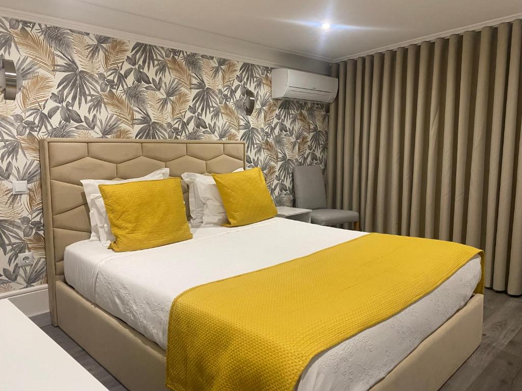 波尔图GuestHouse Marquês的一间卧室配有一张带黄色枕头的大床