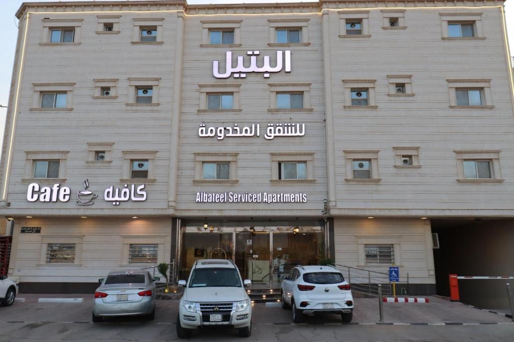 利雅德Al Bateel Furnished Apartments的前面有汽车停放的建筑