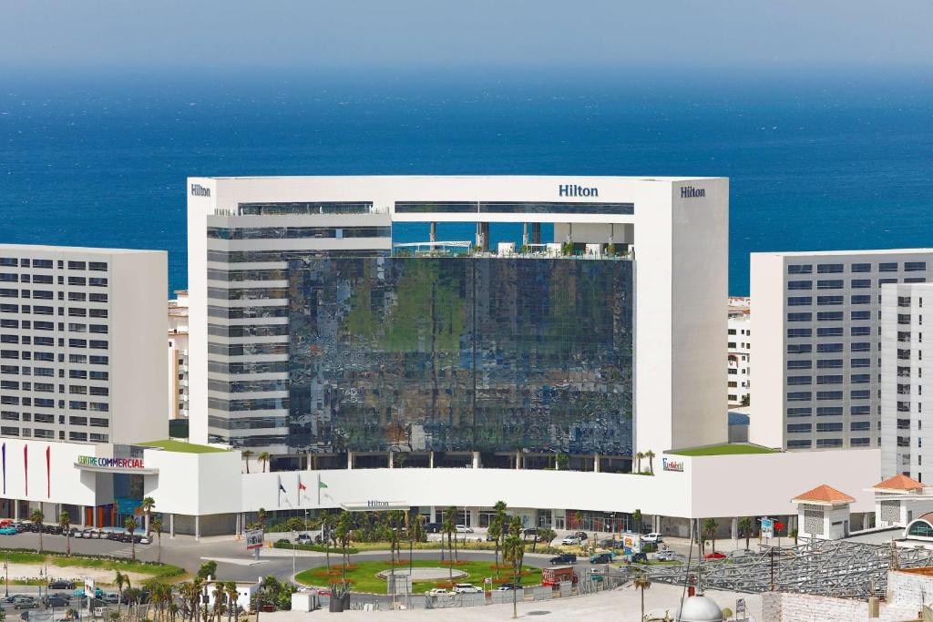 丹吉尔Hilton Tanger City Center的一座大白色的建筑,位于海洋前