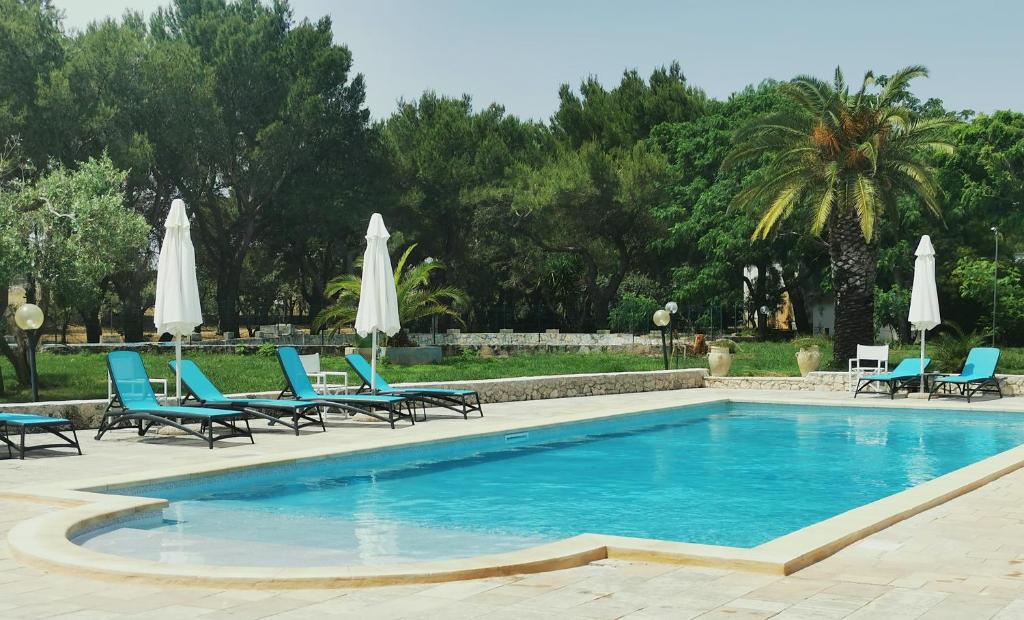 圣凯撒利亚温泉Residence Conchiglia San Giovanni的一个带蓝色椅子和遮阳伞的游泳池
