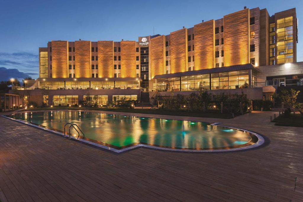 阿瓦诺斯阿凡诺斯卡帕多西亚希尔顿逸林酒店的建筑前的一座带游泳池的建筑